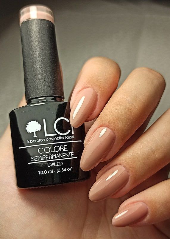 Flacone di smalto accanto a unghie smaltate nude. Flacone nero con logo e testo bianchi. Tonalità: Nude 03.