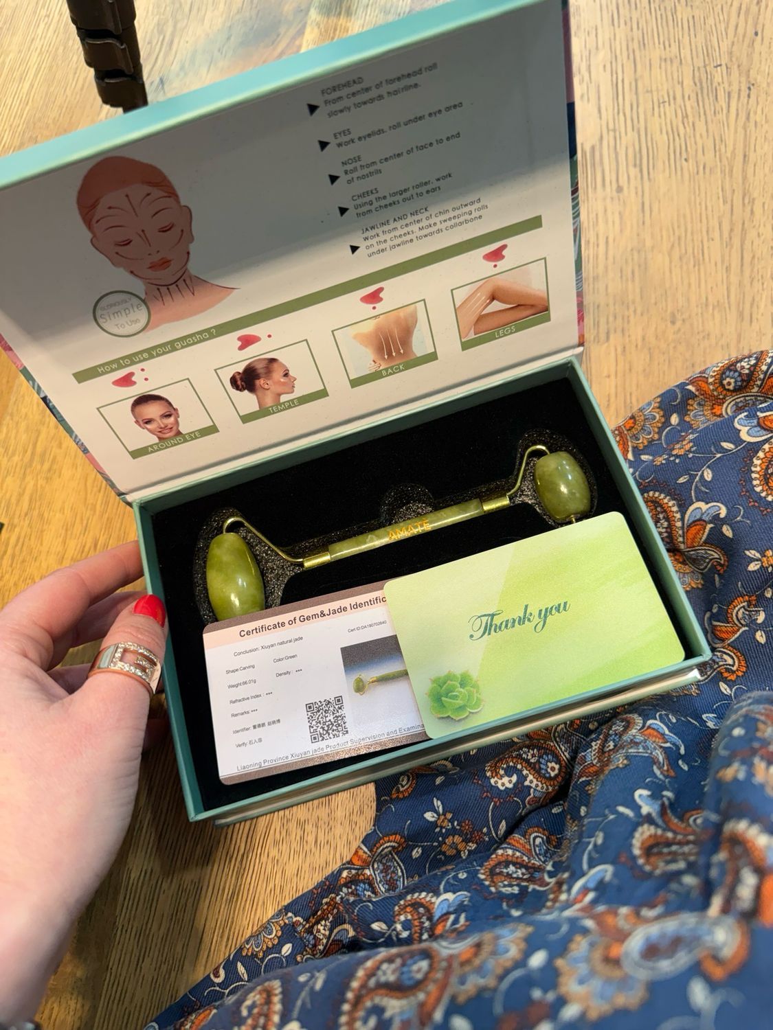 Confezione aperta con rullo in giada, pietra Gua Sha, certificato e biglietto di ringraziamento. Confezione con istruzioni.