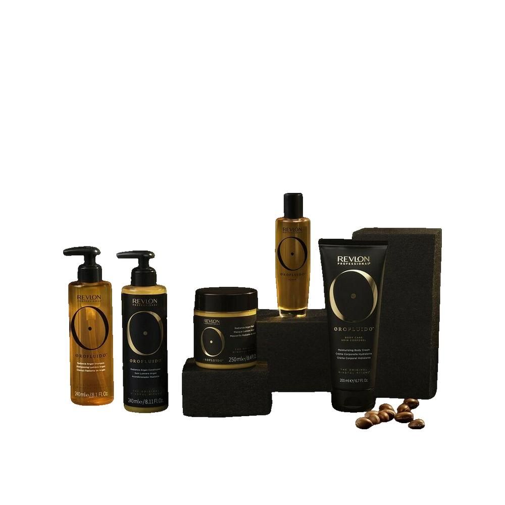 Prodotti Orofluido su blocchi neri. Flaconi, vasi e tubetto in oro e nero. Semi di argan accanto.